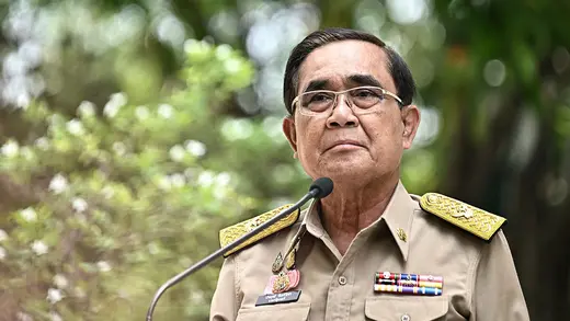 Thailand's prime minister, dressed, in military uniform, speaks into a microphone.