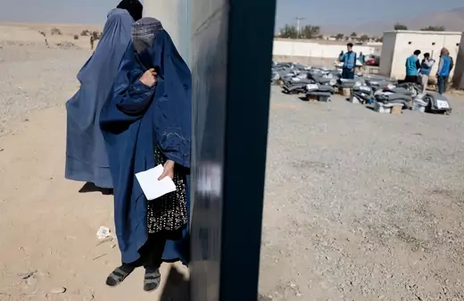 A displaced Afghan woman waits to receive aid supply from UNCHR agency outside a distribution center on the outskirts of Kabul, Afghanistan October 28, 2021.
