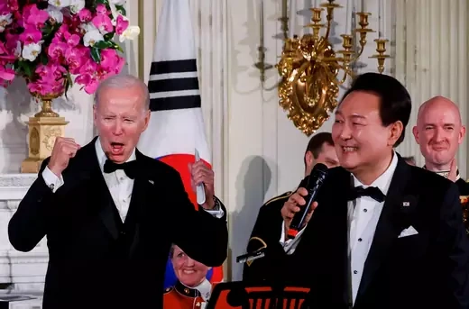 President Yoon sings "American Pie" into a microphone while Biden cheers with his hands raised.