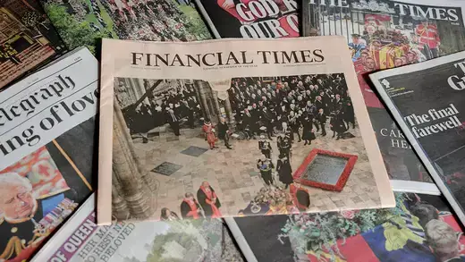 Financial Times newspaper shown with other newspapers around it