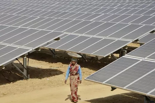 A woman worker walks through the installed solar modules at the Naini solar power plant in the northern Indian city of Allahabad.