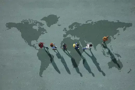 People walking across a world map painted on asphalt.