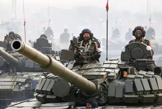 Soldiers stand inside tanks during a military parade.