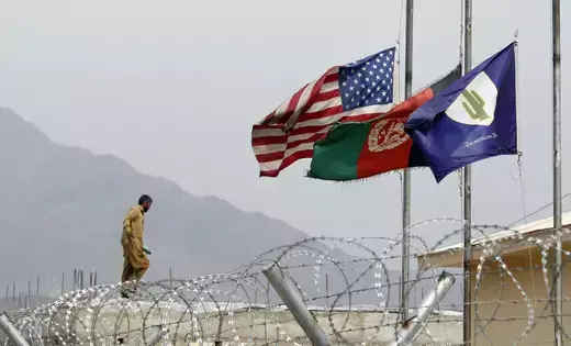 An Afghan working in a U.S military base walks near half mast flags of United States, Afghanistan and Task Force Cacti after a U.S. Army officer was killed by an IED (improvised explosive device) during a patrol in Pesh Valley, at Forward Operating Base Joyce in Kunar province, eastern Afghanistan March 18, 2012.