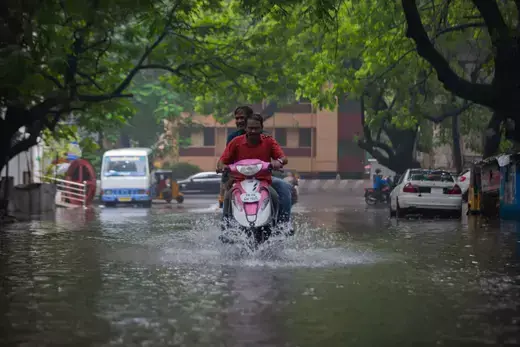 A man rides a motorcycle on a flooded street in Chennai, India in November 2021.