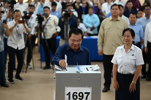 Onlookers watch as Cambodian President Hun Sen places a ballot in a ballot box