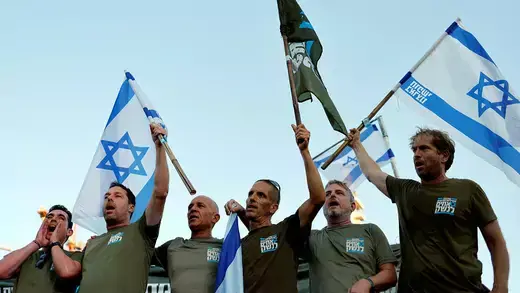 Israeli military reservists in green hold Israeli flags during protest against the government's judicial overhaul.
