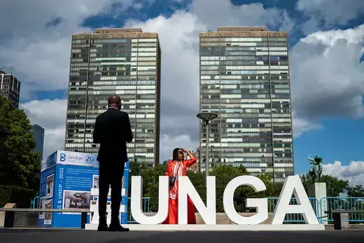 A large UNGA sign is photographed in front of the United Nations buildings.
