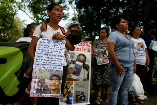A group of protesters as viewed holding homemade signs with images of their relatives.