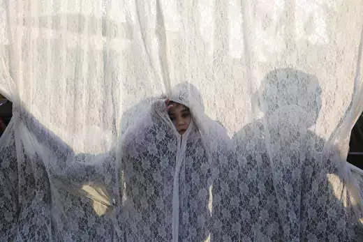 A girl stands behind a curtain that separates between men and women at the gravesite of Rabbi Yisrael Abuhatzeira, a Moroccan-born sage and Kabbalist also known as the Baba Sali, during an annual pilgrimage held on the anniversary of his death in the southern Israeli town of Netivot, January 13, 2016.