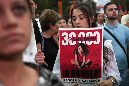 A woman at a protest holds a sign decrying humanitarian conditions facing children in Nagorno-Karabakh