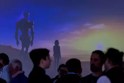 A group of people stand in front of a projected screen of an AI generated image of a robot and a woman standing in front of a sunset.