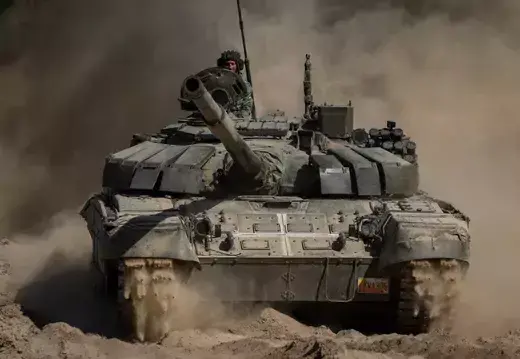 A Ukrainian tank as viewed driving over dusty terrain. 