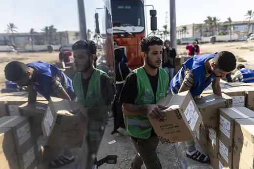 Young Egyptian volunteers load boxes of food and supplies onto aid trucks bound for Gaza