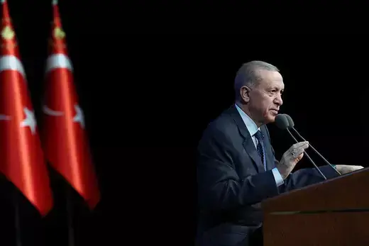 Turkish President Recep Tayyip Erdogan speaks at a lectern. Two Turkish flags are seen behind him.