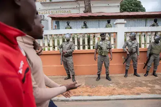 Two people walk by Mozambique police forces guarding the Technical Secretariat of Electoral Administration in Maputo Mozambique on October 17, 2023. 
