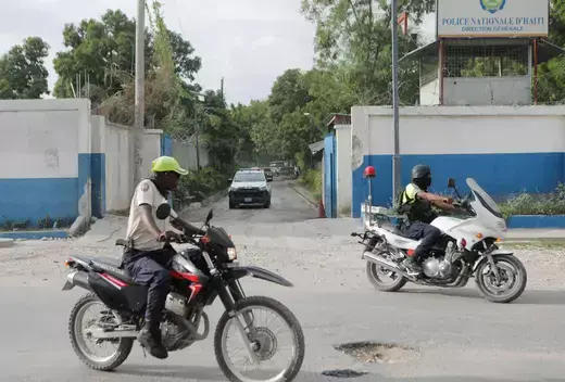 A convoy of cars from the Haitian National Police (PNH) are pictured being led by two men on motorcycles. 