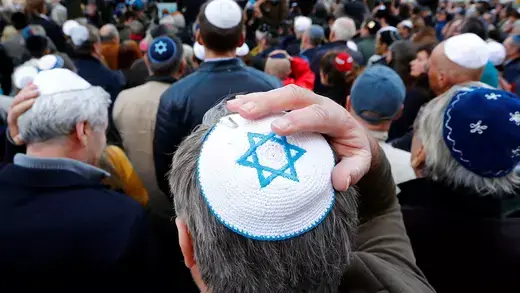 People wear kippas as they attend a demonstration in front of a Jewish synagogue, to denounce an anti-Semitic attack.