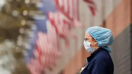 A nurse wearing personal protective equipment stands outside Elmhurst Hospital.