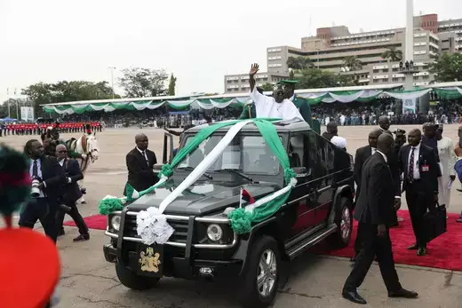 Nigeria's President Bola Tinubu waves to the crowd on the top of a ceremonial vehicle.