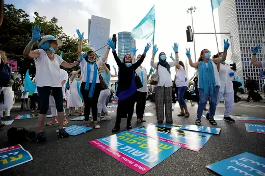 Women gesture as they take part in a protest, organised by "Women Wage Peace" grassroots movement, against Israel's planned annexation of part of the Israeli-occupied West Bank, outside government offices in Tel Aviv, Israel June 18, 2020. The placards in Hebrew read," Stop the annexation, make peace" and in Arabic, "Women make peace".