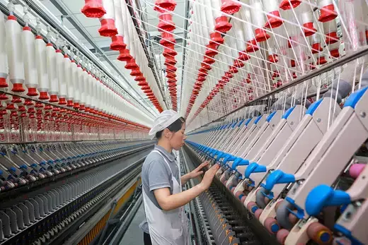 Factory worker making textiles on a large industrial machine.