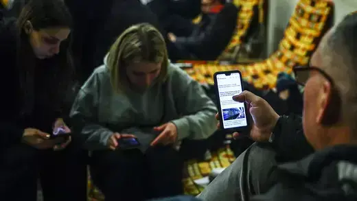 Displaced Ukrainians check their phones in a Polish train station.