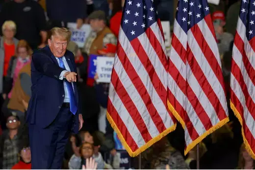Former President Donald Trump as viewed walking past American flags at a campaign rally.