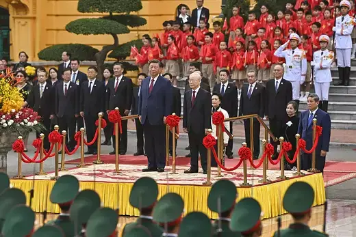 Chinese and Vietnamese leaders stand on a yellow podium in suits.