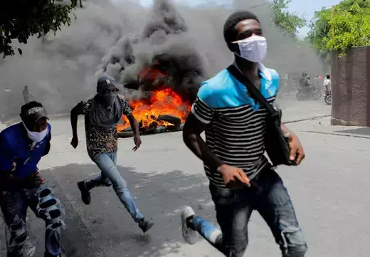 Men run next to burning tires during a protest demanding an end to gang violence, in Port-au-Prince, Haiti on August 14, 2023