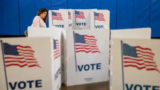 Woman voting with several voting booths with the American flag surrounding her.