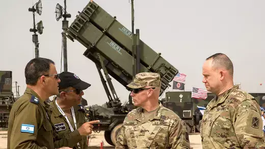 U.S. and Israeli army officers talk in front a Patriot missile defense system.