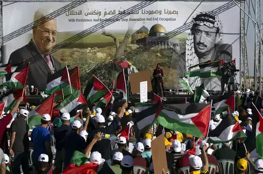 Palestinians wave their national flag as they rally beneath images of President Mahmoud Abbas and his predecessor, Yasser Arafat