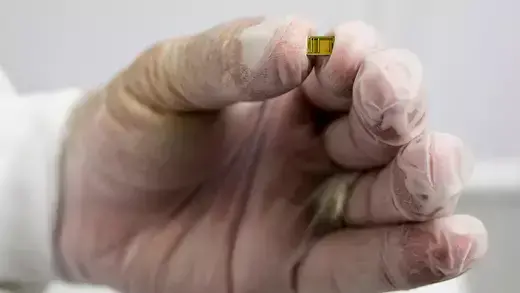 Hand wearing gloves holding a yellow semiconductor chip
