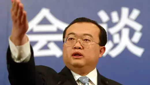 Liu Jianchao speaking at a news conference in Beijing with arm raised.