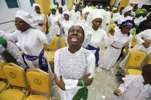 Churchgoers in Nigeria worship in white clothing in a room of about fifty to one hundred members.
