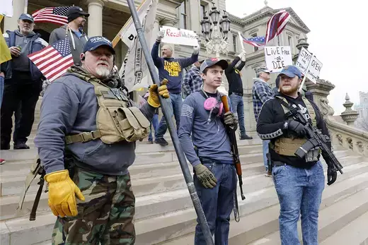 Armed civilian men stand on the steps of the Michigan State Capitol in Lansing, taking part in a protest against Gov. Gretchen Whitmer's expanded stay-at-home order during the Covid-19 pandemic.
