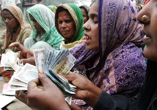 Bangladeshi women count money for repayment to a microcredit bank at Dowtia village near Dhaka on January 20, 2004.