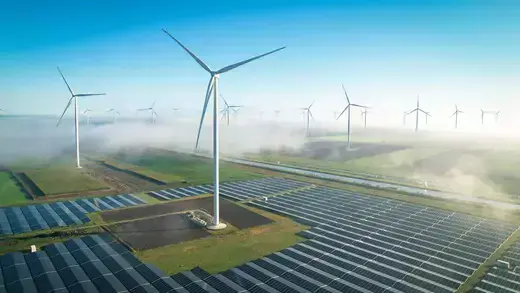 Solar energy fields and wind turbines seen from the air in foggy conditions during an autumn morning