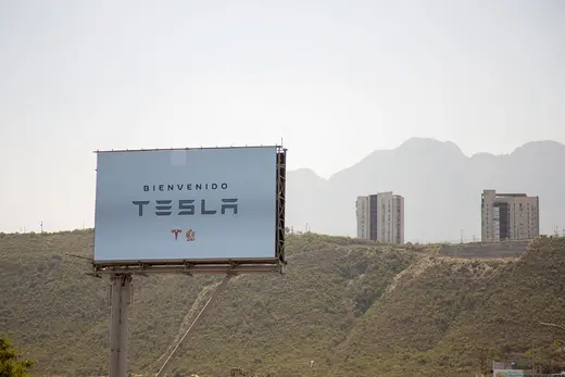 Arid landscape with a Tesla sign in the foreground.