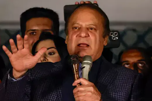 Former Prime Minister of Pakistan Nawaz Sharif gestures with his hand while holding a microphone speaking to a group.