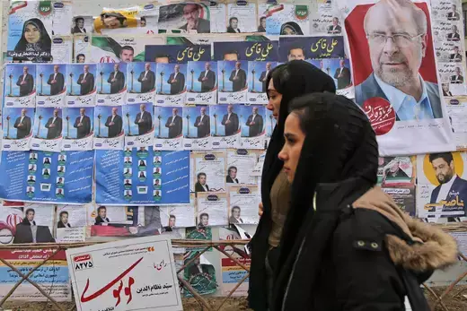 A view of a billboard with candidate propaganda pictures, placards on it as a people walk past in a street of the Iranian capital Tehran on February 28, 2024. Legislative elections are scheduled to take place in the country on 1 March 2024.