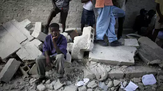 A boy in Haiti sits next to the remains of a destroyed school after an earthquake.
