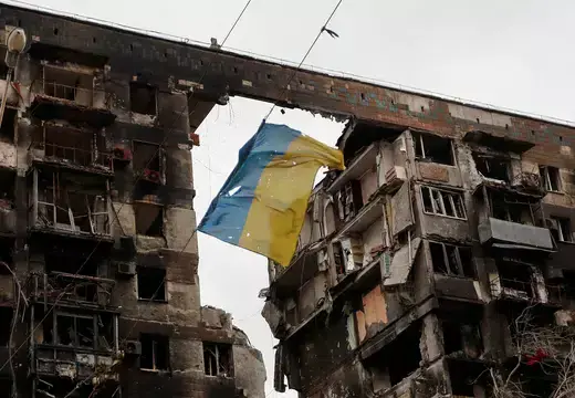 A torn flag of Ukraine hung on a wire in front an apartment building destroyed during Ukraine-Russia conflict 