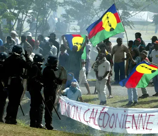 Pro-independance demonstrators hold a Kanak flags as they face French riot police during a protest outside the New Caledonian northern province assembly while French President Jacques Chirac was paying a visit to the New Caledonian northern city of Kone on July 25, 2003.