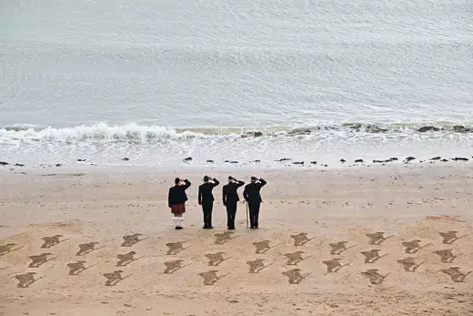 Veterans salute as the tide comes in on a sand artwork depicting soldiers ahead of the 80th anniversary of the D-Day landings, in Broadstairs, Britain, on May 22, 2024.