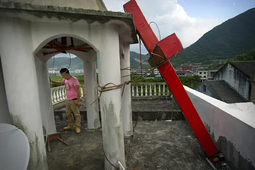 Christian leader stands on Protestant church after Chinese government workers came down to cut down the building's cross on July 29, 2015.