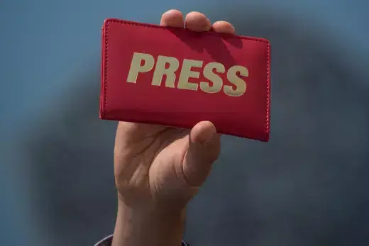 Journalist holding press pass.