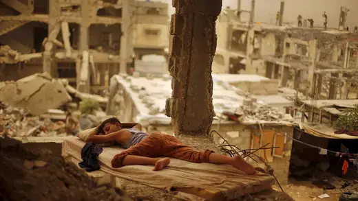 Palestinian boy sleeps on a mattress inside the remains of his family's house in Gaza.