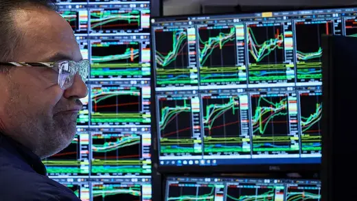 Trader at the New York Stock Exchange sits at his station and analyzes charts.